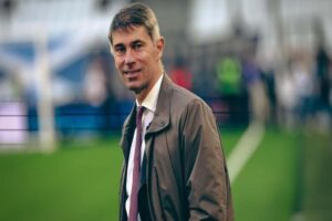 Frederic Massara passeggia sorridente sul campo da gioco