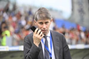 Frederic Massara in primo piano e mentre parla al cellulare